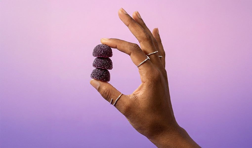 Lifestyle image on a hand holding 3 Dreamscape Gummies