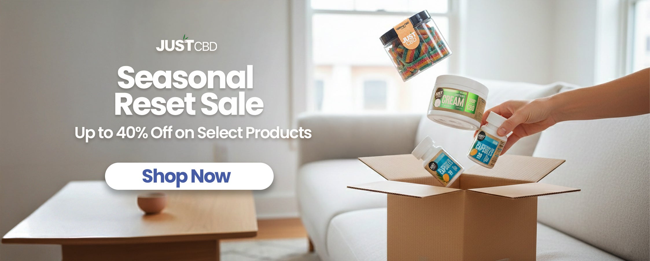Person unpacking a box of JustCBD products with promotional text overlay.