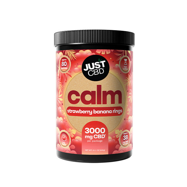 A black plastic tub of Just CBD Calm supplement with a black lid, featuring a label with red and pink strawberry banana rings graphics and a beige circle in the center.